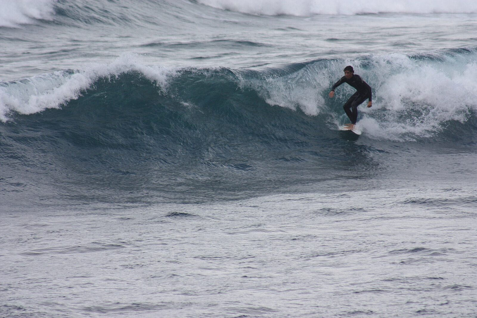 A surfer riding a wave at Caleta de Famara on the northwest coast of Lanzarote