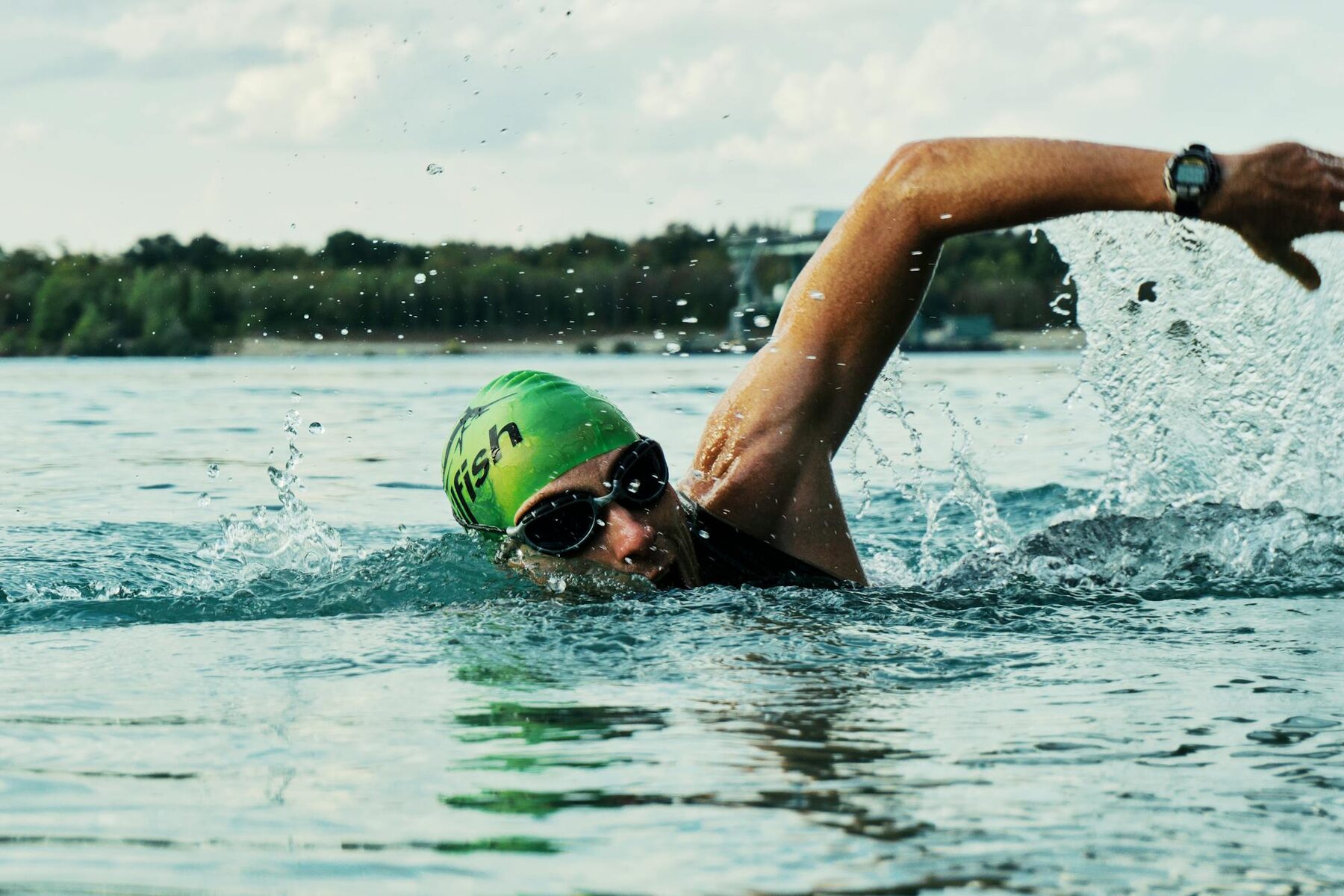 Open water swimmer in green cap front-crawling in calm Atlantic water, Lanzarote, Canary Islands