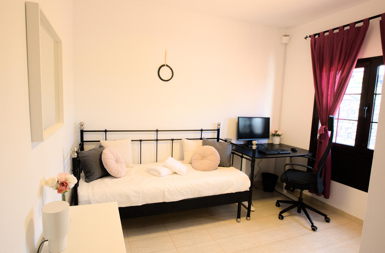 Studio bedroom at Casa Los Alisios with motorised sit-stand desk in seated position and natural light, Costa Teguise, Lanzarote