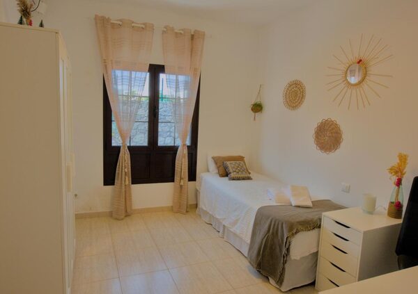 Bright single bedroom with boho wall decor and natural light